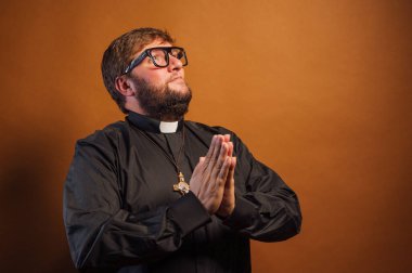 Haçlı ve siyah gömlekli bir rahibin portresi dua ediyor..