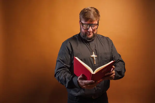 聖書を保持する十字架と黒シャツを持つ司祭の肖像画 — ストック写真