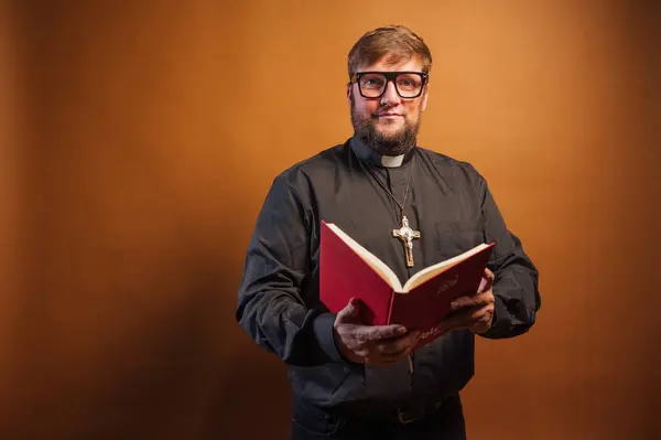 一个拿着十字架和黑色衬衫拿着圣经的牧师的画像 — 图库照片