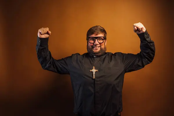 強さの象徴として腕を示す十字架を持つ司祭の肖像画 — ストック写真