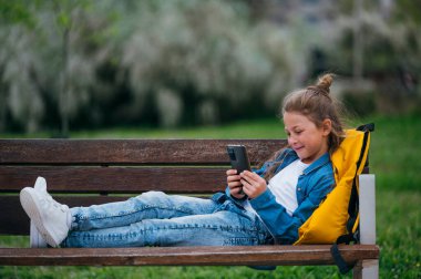 Parkta akıllı telefon kullanan güzel bir çocuk..