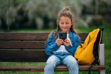 Parkta akıllı telefon kullanan güzel bir çocuk..