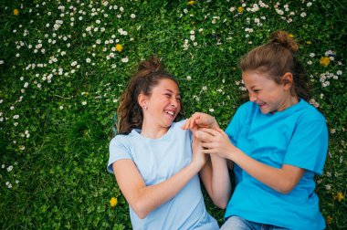 Bahçede oynayan ablası tarafından eşlik edilen bir çocuk..