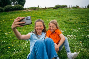 Bahçede oturan akıllı telefonu kullanan ablası tarafından eşlik edilen bir çocuk..