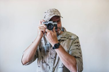 Askeri üniforma giyen ve silahla nişan alan yakışıklı bir adam..