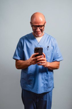 Açık mavi ceket giyen ve akıllı telefon kullanan bir fizyoterapistin portresi..