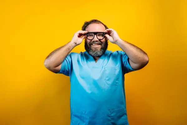 stock image Doctor in blue coat on yellow background smiling.