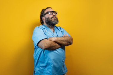 Sarı arka planda mavi ceketli ve düşünceli bir doktor..