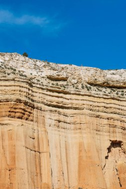 Kızıl kaya oluşumları ve mavi gökyüzü ile çöl manzarasının çarpıcı görüntüsü..