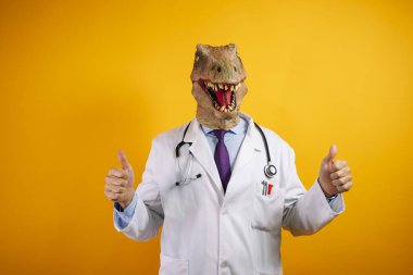 Sarı arka planda dinozor maskeli bir doktor. Barış jesti yapıyor..