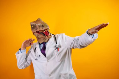 Sarı arka planda dinozor maskeli bir doktor. Jestler yapıyor..