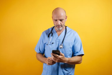 Beyaz önlüklü, dost canlısı bir doktor elinde akıllı bir telefon tutuyor. Modern sağlık ve iletişimi öneriyor..