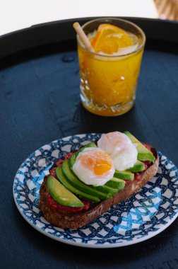 Lezzetli ve sağlıklı bir avokado tostu üzerinde mükemmel haşlanmış yumurta ve canlı domates sosu..