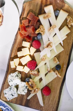 Bir ahşap peynir tahtasının üzerinde çeşitli peynirlerden oluşan güzel bir kare.,
