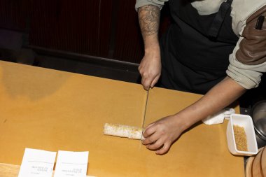 Bir şefin ellerini dikkatlice yakın plan yap. Suşi rulosunu tahtada dikkatlice kes..