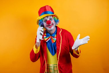 Mutlu palyaço akıllı telefon kullanır, parlak sarı arka plan.