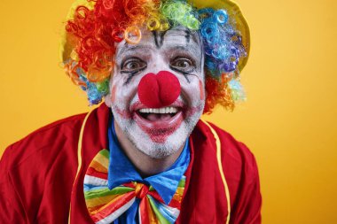 Canlı sarı arka plana karşı renkli kostümlü mutlu palyaço..