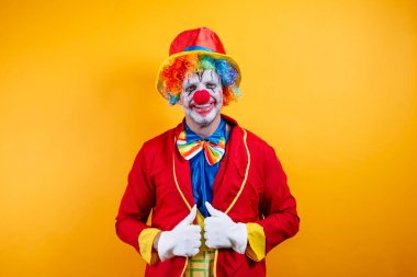 Canlı sarı arka plana karşı renkli kostümlü mutlu palyaço..