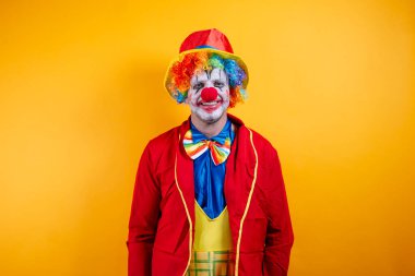 Canlı sarı arka plana karşı renkli kostümlü mutlu palyaço..