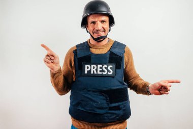 Kurşun geçirmez yelek giyen gazeteci iki tarafı da işaret ediyor..