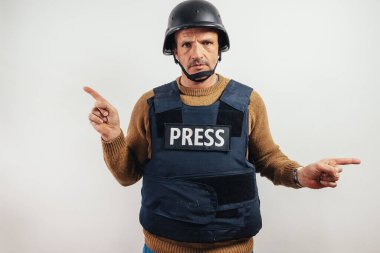 Kurşun geçirmez yelek giyen gazeteci iki tarafı da işaret ediyor..