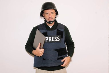 Erkek gazeteci dizüstü bilgisayar tutuyor, ciddi görünüyor.