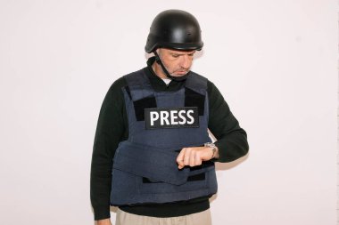 Gazeteci kask takıp saati kontrol ediyor