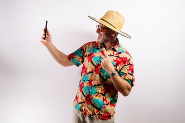 Orta yaşlı bir adam tatilde neşeli bir selfie çekiyor.