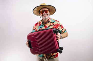 Kırmızı bavullu turist gülümsüyor.