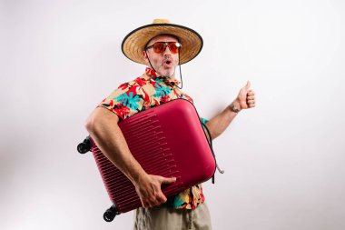 Komik turist bavulunu kucaklıyor ve başparmağını kaldırıyor.