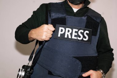 Beyaz arka planda kurşun geçirmez yelek giyen gazeteci.