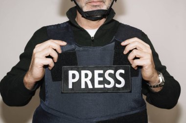 Beyaz arka planda kurşun geçirmez yelek giyen gazeteci.