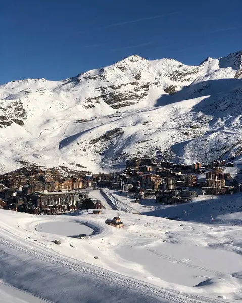 Berrak mavi gökyüzünün altındaki dağlarda yuva yapmış, karla kaplı bir dağ köyünün nefes kesici manzarası mükemmel bir kış manzarası sergiliyor.