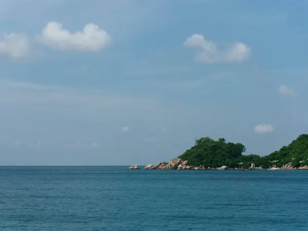 Berrak bir gökyüzünün altında sakin turkuaz sularla çevrili yemyeşil bir adanın huzurlu manzarası. Rahatlamak ya da ada maceraları için mükemmel.