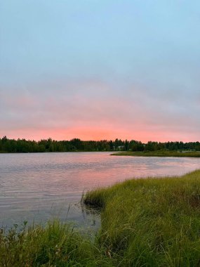 Önplanda Çimen ve Sakin Göl Üzerinde Pastel Günbatımı