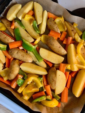 Havuç, patates ve dolma biber de dahil olmak üzere canlı sebzelerden oluşan bir karışım, kızartılmaya hazır bir yemek tepsisi üzerinde düzenlenir. Renkli çeşitlilik sadece görsel olarak çekici değil aynı zamanda besleyici ve lezzetli bir yemek vadediyor..