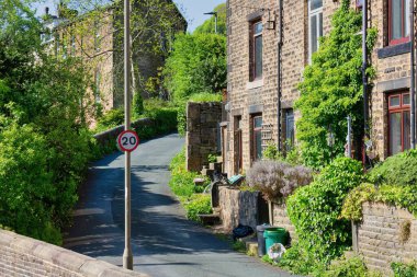 Hebden Köprüsü - Batı Yorkshire - Büyük Britanya 'da güneşli bir günde küçük bir taş ve bitkilerle dar bir caddenin dikey görüntüsü.