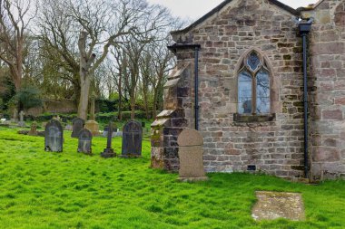 Güneşli bir günde mezarlıkta bir taş haç ve Heysham 'da bir kilise - Lancashire - İngiltere