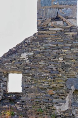 Barmouth, Gwynedd- Wales, İngiltere 'de yıkık dökük bir ev penceresi olan eski, taştan bir çatı.