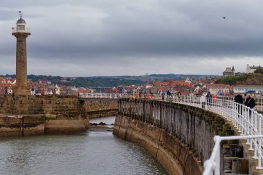 Deniz fenerli eski köprü iskelesi ve Whitby 'deki insanlar - Kuzey Yorkshire - Birleşik Krallık