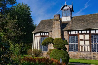 a low angle shot of a building with a green tree and a brick wall - Rufford Old Hall - Rufford - Lancashire - united kingdom clipart