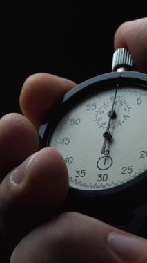 Siyah arka planda siyah analog kronometre var. Zaman eski kronometreyle başlıyor. Erkek başlatma düğmesine basar. Spor ya da iş konsepti, başarılı takım çalışması ve geri sayım süresi