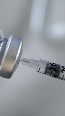 Doktor ya da hemşire aşıyı şırınga ve iğneyle hazırlar. Tıbbi şişeler enjeksiyon için hazır. Aşılama ve aşılama sürecine odaklan. Sağlık ve hastalıkların önlenmesi için gerekli
