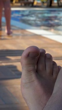 Tatilde yüzme havuzunda insan ayağı dinlenir. Temiz su arka planı. Erkek eğleniyor, mutlu turist. Şehir yaşamından cennete kaçmak.