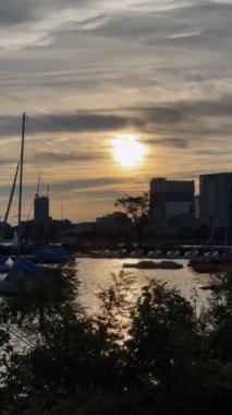 Rıhtım manzarası, yatlar, dalgalar, setin üzerindeki yeni bina, ilk hattaki gayrimenkul. Akşam havası, gün batımı, yüksek kontrastlı, turuncu gökyüzü ve bulutlarda batan güneş..