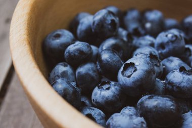Tahta bir kasede sulu olgun büyük yaban mersinli fotoğraf kompozisyonu.