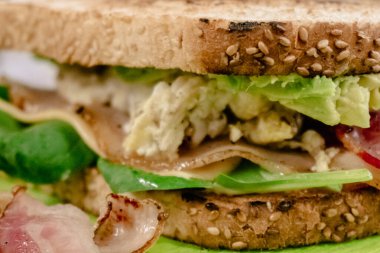 Jambonlu sulu sandviç, taze yeşil salata yaprakları ve püre avokado. Favori lezzetli bir kahvaltı fotoğrafı..