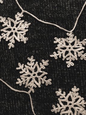 Koyu arkaplanda çelenk şeklinde örülmüş beyaz kar taneleri. Kış tatillerinin sembolü olarak kar taneleri doğru atmosferi ve şenlikli sıcak havayı yaratır..