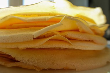 Yeni yapılmış ince krep yığınının yakın çekimi, narin, altın tabakalarını hafif ışıklandırmayla aydınlatıyor.