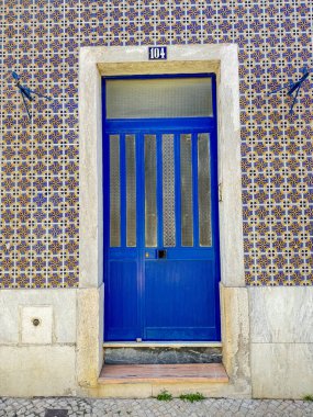 Büyüleyici mavi ahşap bir kapı geleneksel bir azulejo fayanslı ön cephede